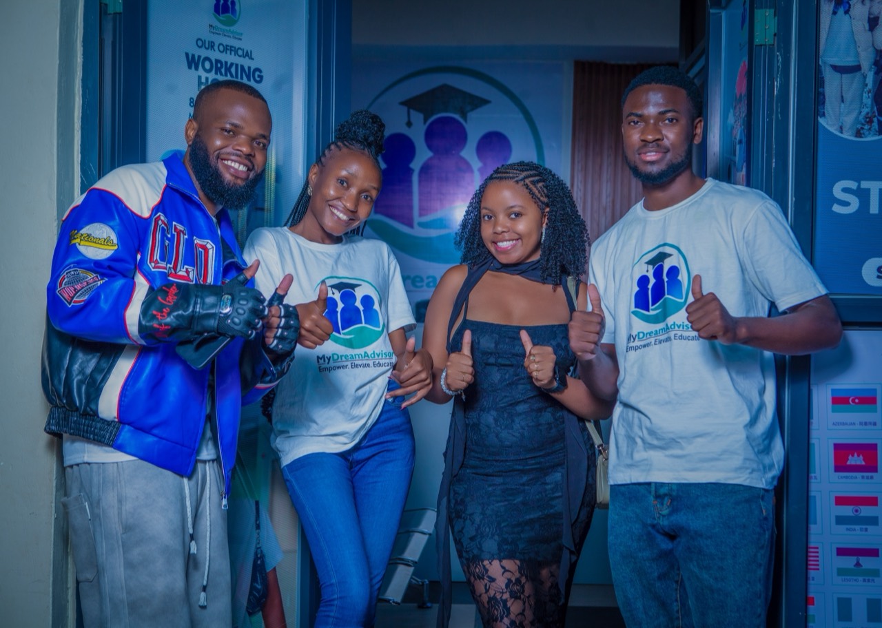 Four people smiling and giving thumbs-up outside the MyDreamAdvisor office